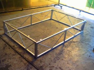 Repaired motorcycle rear frame photographed against workshop screens