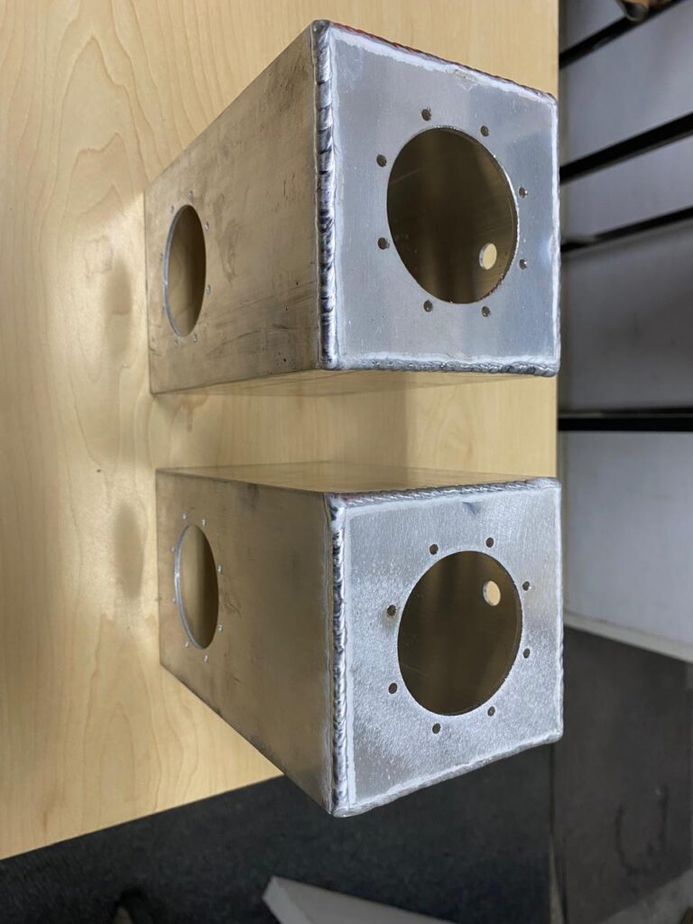 Two fabricated aluminium housings with machined openings.